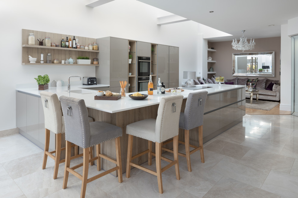 This is an example of a contemporary u-shaped open plan kitchen in Other with an undermount sink, flat-panel cabinets, beige cabinets, black appliances, a peninsula, beige floor and white benchtop.