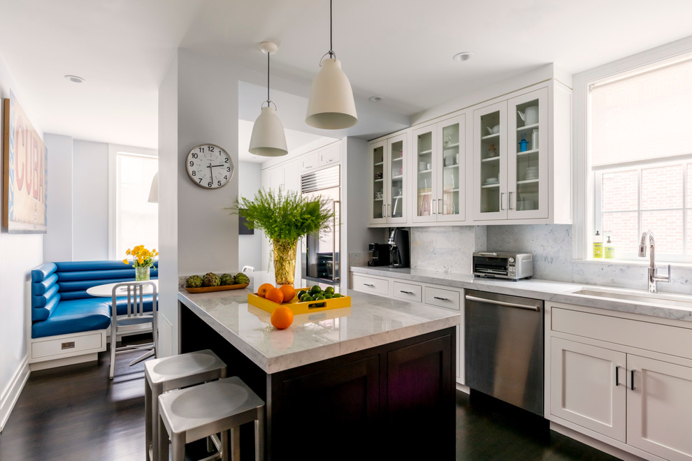 This is an example of a transitional eat-in kitchen in New York with an undermount sink, shaker cabinets, white cabinets, white splashback, dark hardwood floors and with island.