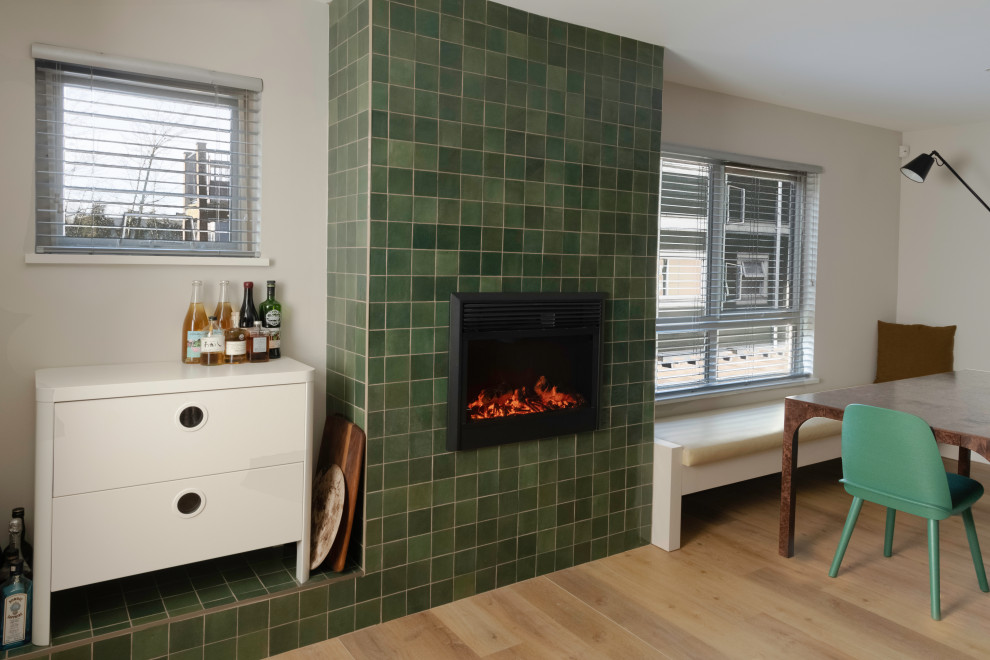 バンクーバーにある低価格の小さなミッドセンチュリースタイルのおしゃれなダイニングキッチン (白い壁、淡色無垢フローリング、標準型暖炉、タイルの暖炉まわり、茶色い床、板張り天井、板張り壁) の写真