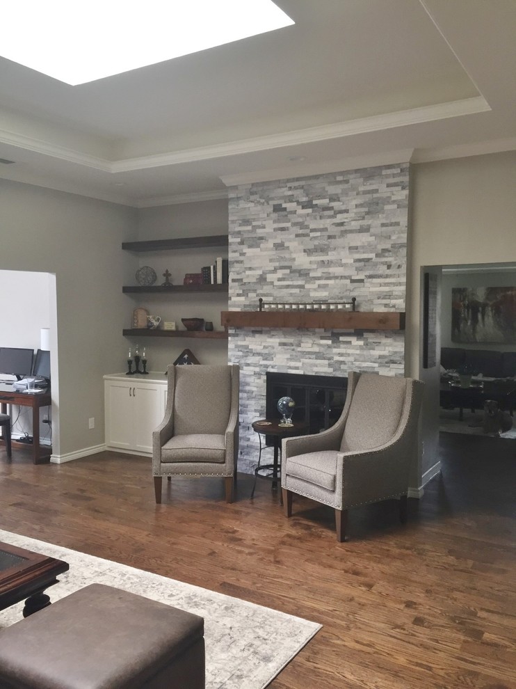 This is an example of a mid-sized transitional open concept family room in Dallas with grey walls, medium hardwood floors, a standard fireplace, a stone fireplace surround and brown floor.