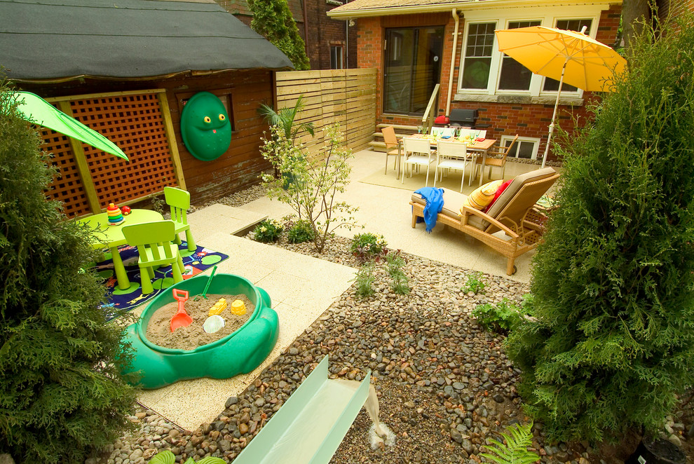 This is an example of an eclectic backyard garden in Toronto with a water feature.