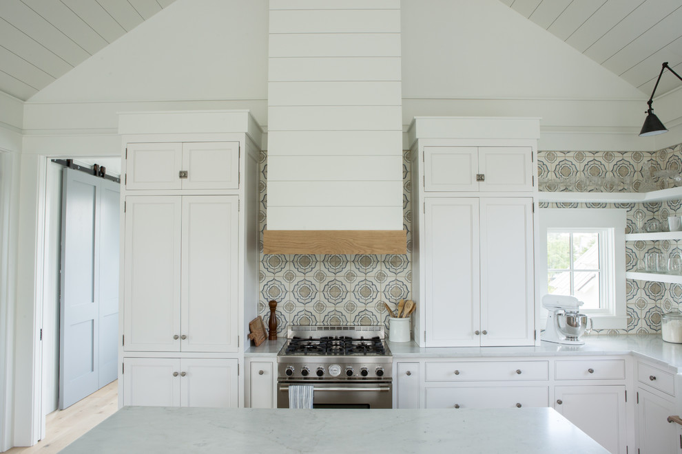Inspiration for a mid-sized country l-shaped open plan kitchen in Charleston with a farmhouse sink, shaker cabinets, white cabinets, marble benchtops, terra-cotta splashback, panelled appliances, light hardwood floors, with island and white benchtop.