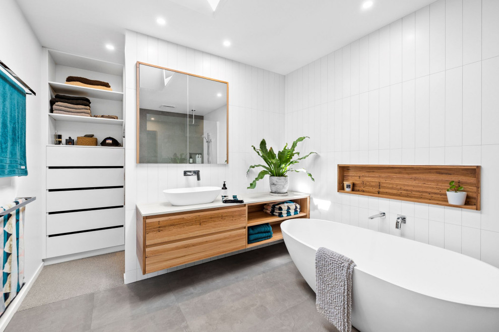 Photo of a large contemporary master bathroom in Geelong with flat-panel cabinets, a freestanding tub, white tile, ceramic tile, ceramic floors, engineered quartz benchtops, grey floor, white benchtops, a single vanity, a floating vanity, medium wood cabinets and a vessel sink.