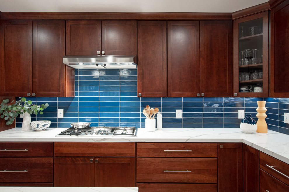 Immagine di una grande cucina chic con lavello a doppia vasca, ante in stile shaker, ante marroni, paraspruzzi blu, paraspruzzi con piastrelle di vetro, elettrodomestici in acciaio inossidabile, parquet chiaro, pavimento giallo e top bianco