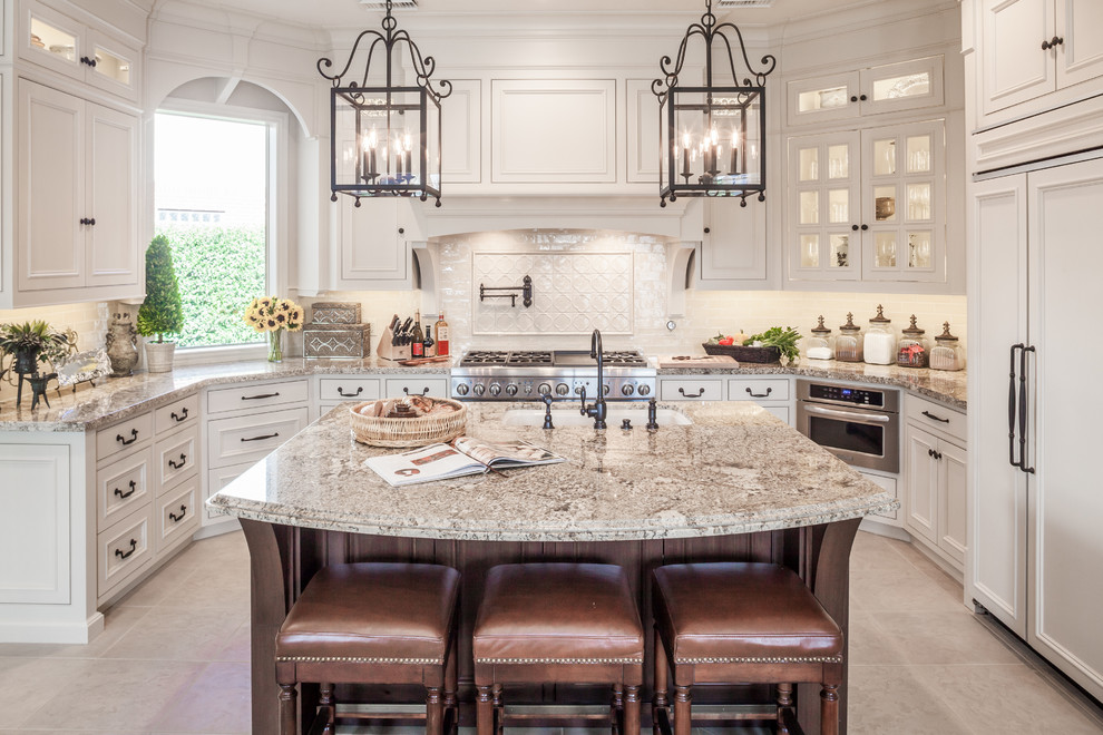 Design ideas for a traditional u-shaped kitchen in Houston with an undermount sink, granite benchtops, panelled appliances, beaded inset cabinets, beige splashback, ceramic splashback, ceramic floors, with island, beige floor, multi-coloured benchtop and white cabinets.