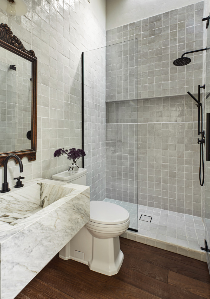 Foto på ett mellanstort medelhavsstil vit badrum med dusch, med en dusch i en alkov, en toalettstol med hel cisternkåpa, vit kakel, perrakottakakel, vita väggar, mellanmörkt trägolv, ett integrerad handfat, marmorbänkskiva, brunt golv och dusch med gångjärnsdörr