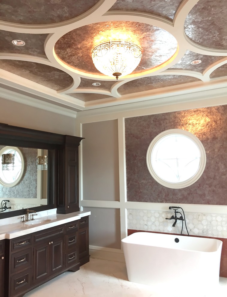 This is an example of a large mediterranean master wet room bathroom in Miami with furniture-like cabinets, dark wood cabinets, a japanese tub, a one-piece toilet, white tile, ceramic tile, multi-coloured walls, travertine floors, an undermount sink, marble benchtops, beige floor, an open shower and white benchtops.