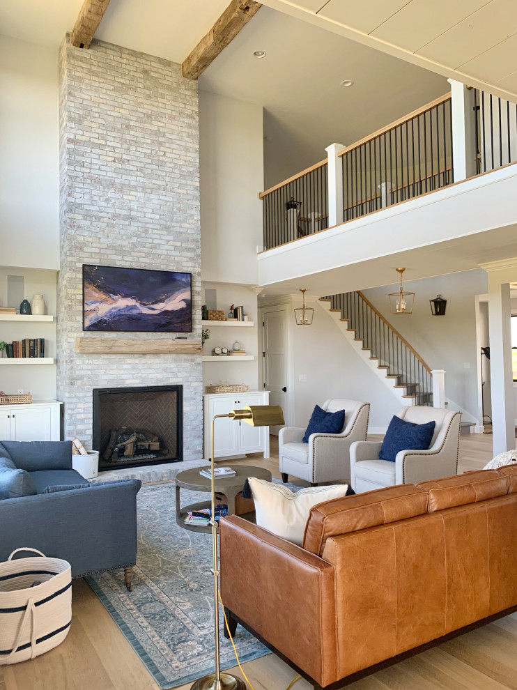 Example of a large farmhouse open concept light wood floor family room design in Other with gray walls, a standard fireplace, a brick fireplace and a wall-mounted tv