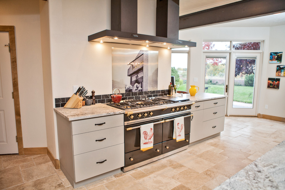 Large industrial l-shaped kitchen in Denver with an undermount sink, flat-panel cabinets, beige cabinets, granite benchtops, panelled appliances, travertine floors, with island, beige floor and multi-coloured benchtop.