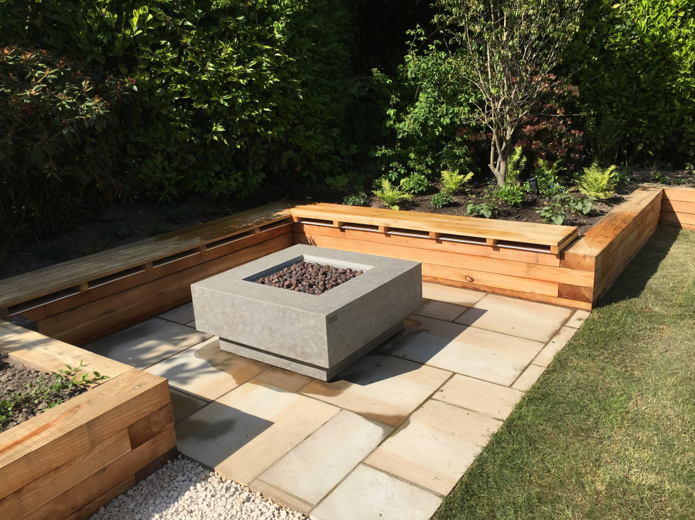 Photo of a mid-sized contemporary backyard garden in Sussex with a retaining wall and natural stone pavers.