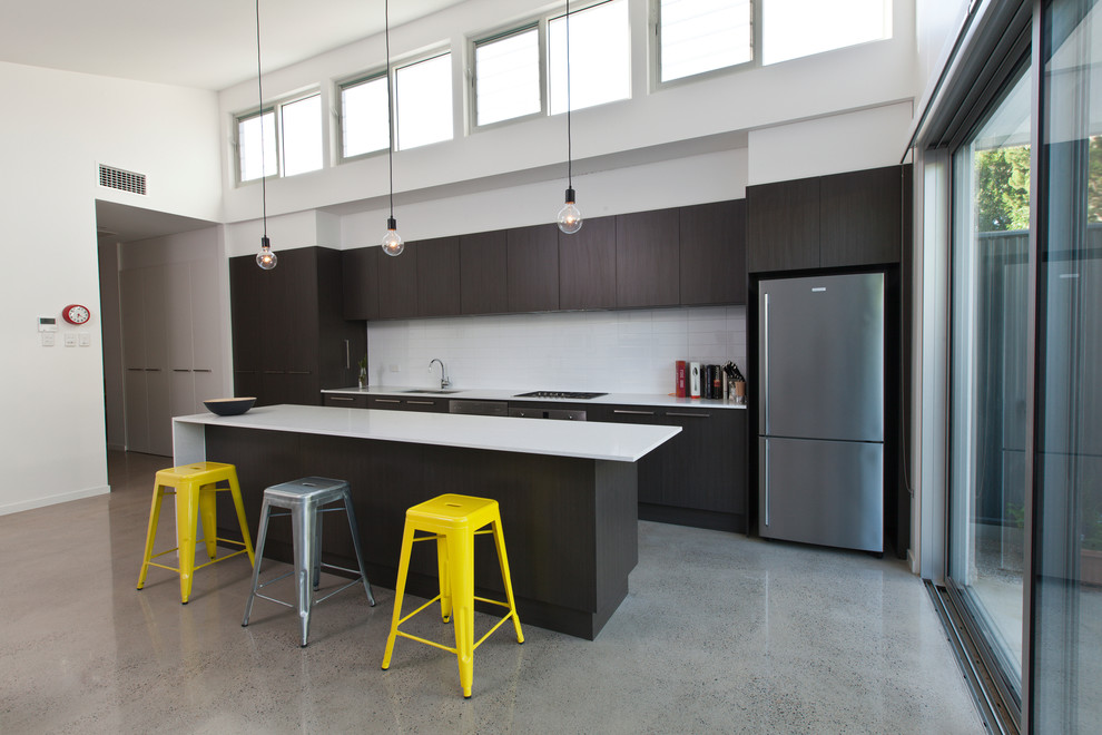 This is an example of a mid-sized contemporary galley eat-in kitchen in Adelaide with an undermount sink, flat-panel cabinets, dark wood cabinets, quartz benchtops, white splashback, ceramic splashback, stainless steel appliances, concrete floors and with island.