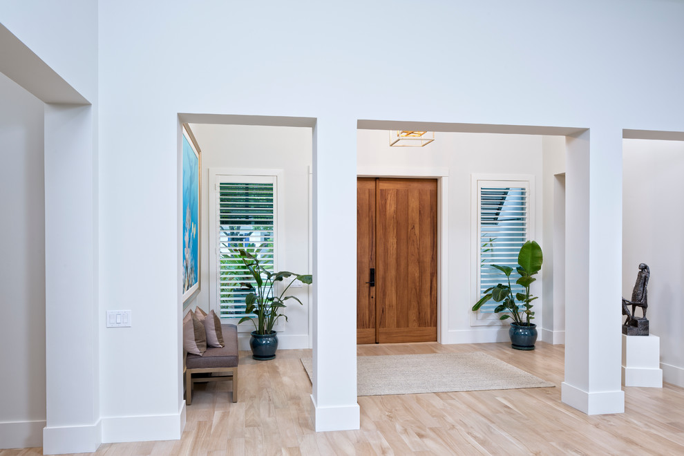 This is an example of a large beach style foyer in Miami with white walls, porcelain floors, a double front door and a medium wood front door.