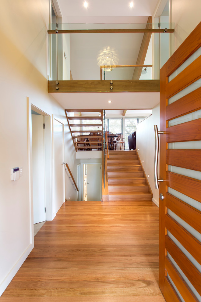 Photo of a contemporary foyer in Sydney with white walls, light hardwood floors and a pivot front door.