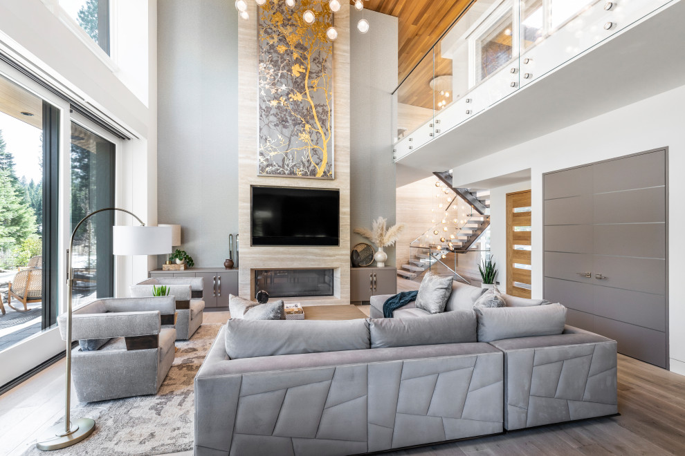 Large contemporary open concept living room with multi-coloured walls, light hardwood floors, a two-sided fireplace, a stone fireplace surround, a wall-mounted tv, beige floor, wood and wallpaper.