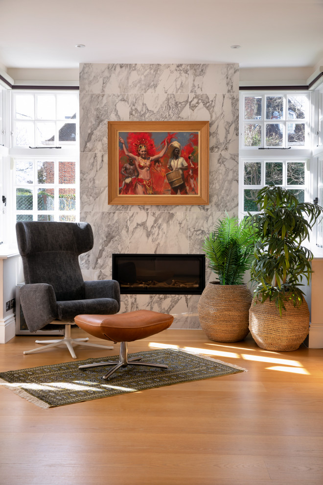 This is an example of an expansive contemporary enclosed living room in London with light hardwood flooring and a standard fireplace.
