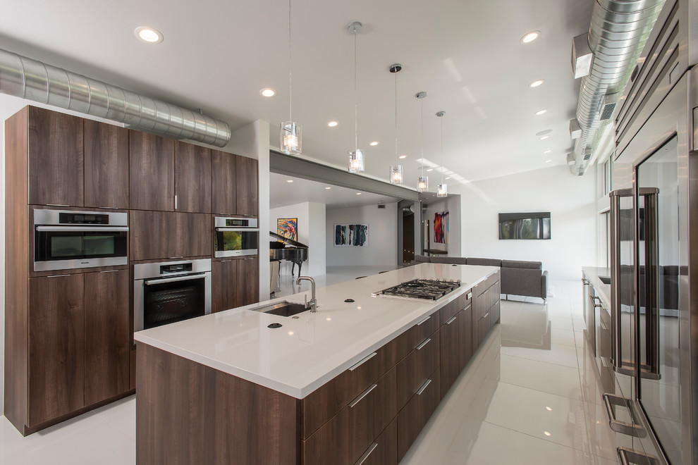 Photo of a contemporary galley kitchen in Phoenix with an undermount sink, flat-panel cabinets, dark wood cabinets, stainless steel appliances and with island.