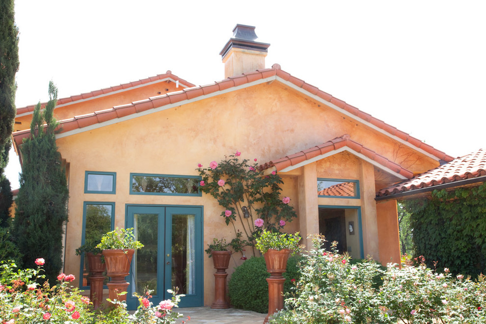 Inspiration for a mid-sized two-storey stucco orange house exterior in Sacramento with a gable roof and a tile roof.