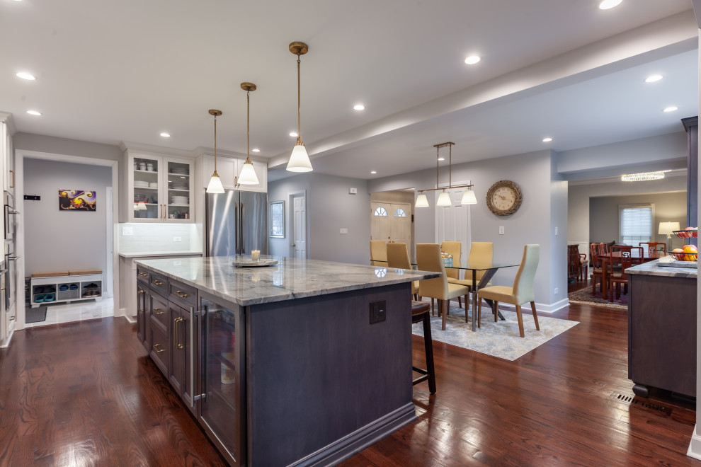 Mid-sized transitional l-shaped dark wood floor and brown floor eat-in kitchen photo in Chicago with an undermount sink, shaker cabinets, gray cabinets, quartzite countertops, white backsplash, porcelain backsplash, stainless steel appliances, an island and gray countertops