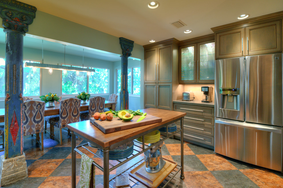 Design ideas for a tropical eat-in kitchen in Tampa with recessed-panel cabinets, wood benchtops, beige splashback, stainless steel appliances, vinyl floors and with island.