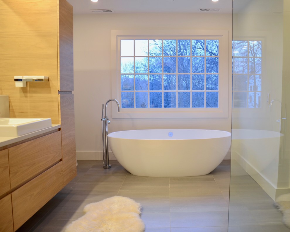 Design ideas for a large modern master bathroom in New York with flat-panel cabinets, light wood cabinets, a freestanding tub, a curbless shower, gray tile, stone tile, white walls, porcelain floors, a vessel sink, concrete benchtops, grey floor and an open shower.