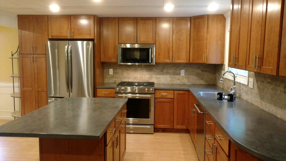 Example of a minimalist kitchen design in New York with an undermount sink, shaker cabinets, solid surface countertops, beige backsplash, ceramic backsplash, stainless steel appliances, gray countertops and an island