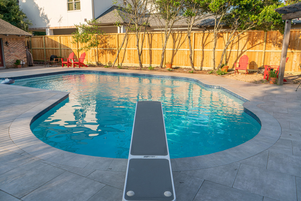 This is an example of a traditional back kidney-shaped swimming pool in Houston with natural stone paving.
