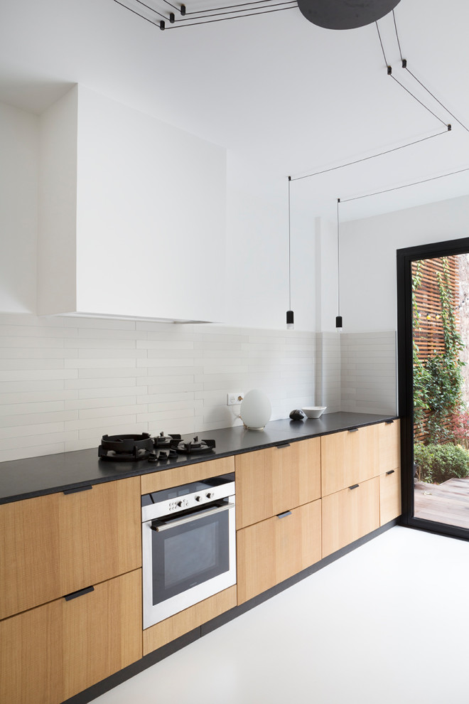 Design ideas for a large contemporary l-shaped eat-in kitchen in Paris with an undermount sink, flat-panel cabinets, beige cabinets, grey splashback, ceramic splashback, panelled appliances, concrete floors, no island, white floor and black benchtop.