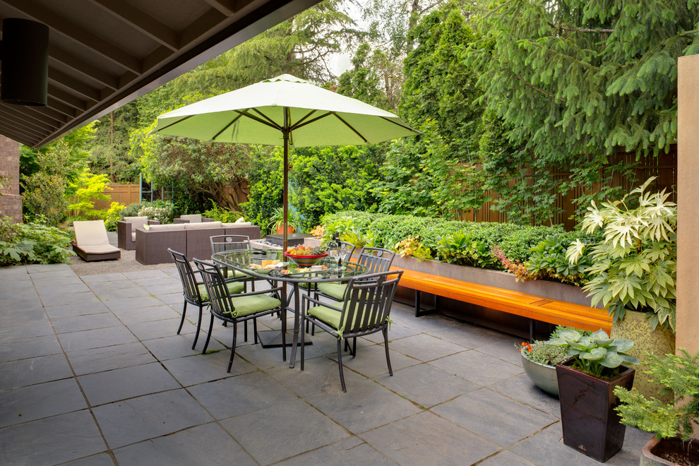 Large contemporary backyard patio in Portland with natural stone pavers, no cover and a container garden.