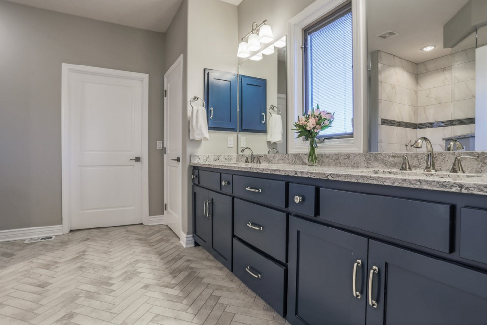 Photo of a large transitional master bathroom in Omaha with recessed-panel cabinets, blue cabinets, an alcove tub, a curbless shower, a one-piece toilet, gray tile, porcelain tile, grey walls, porcelain floors, an undermount sink, quartzite benchtops, grey floor, a shower curtain and multi-coloured benchtops.
