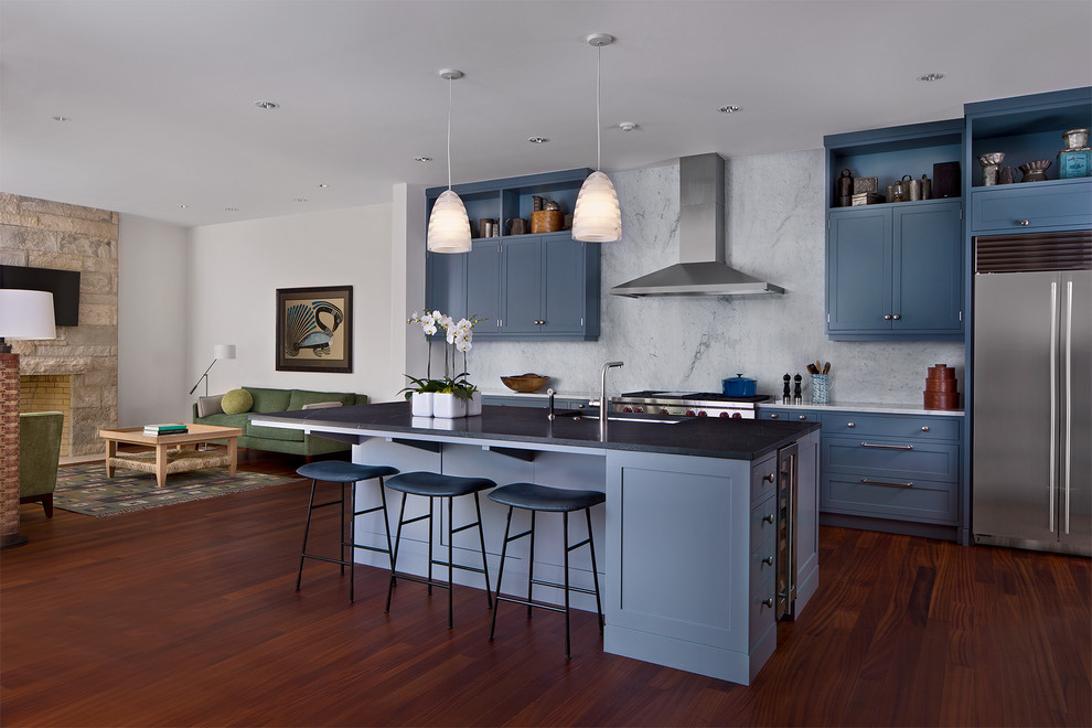 Photo of a mid-sized transitional single-wall open plan kitchen in Detroit with an undermount sink, raised-panel cabinets, blue cabinets, white splashback, stone slab splashback, stainless steel appliances, medium hardwood floors, with island, brown floor, marble benchtops and black benchtop.