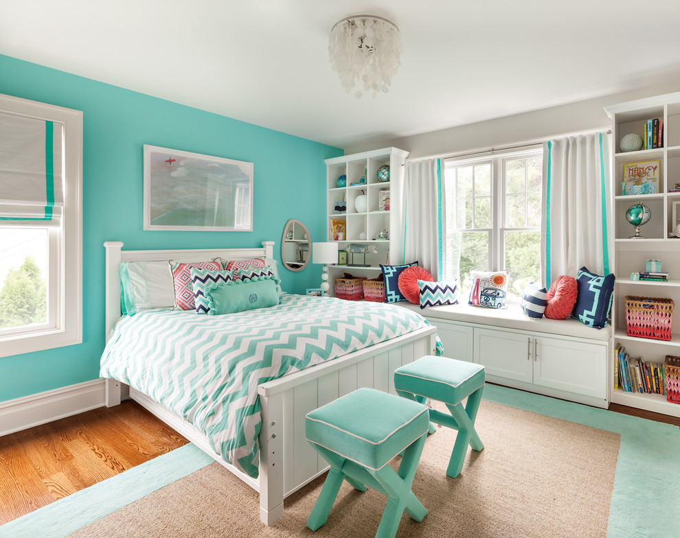 This is an example of a mid-sized transitional kids' bedroom for kids 4-10 years old and girls in New York with blue walls and medium hardwood floors.
