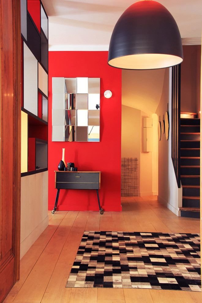 This is an example of a mid-sized contemporary foyer in Paris with red walls and light hardwood floors.