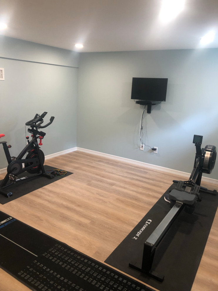 This is an example of a small classic multi-use home gym in New York with blue walls, vinyl flooring and brown floors.