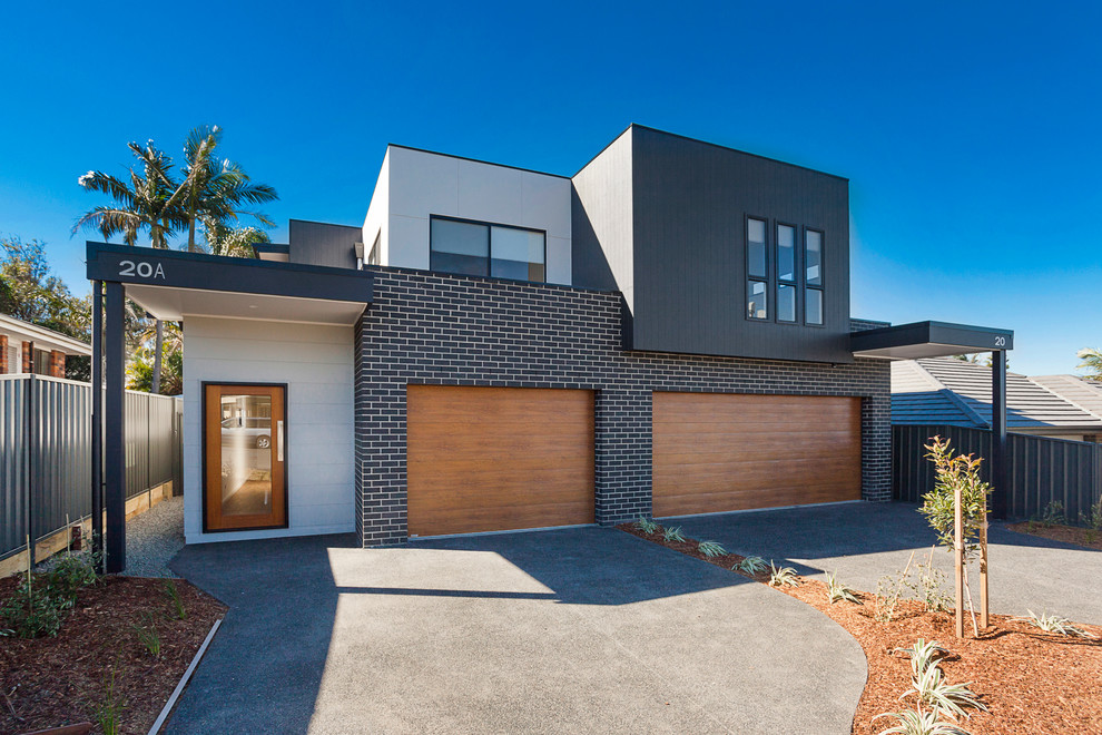 Photo of a contemporary two-storey black duplex exterior in Wollongong with mixed siding and a flat roof.