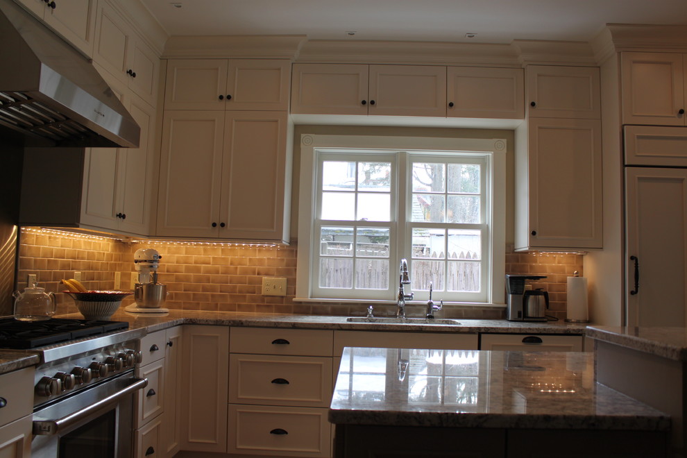 Inspiration for a mid-sized transitional u-shaped eat-in kitchen in Boston with an undermount sink, recessed-panel cabinets, white cabinets, granite benchtops, beige splashback, ceramic splashback, panelled appliances, medium hardwood floors and with island.