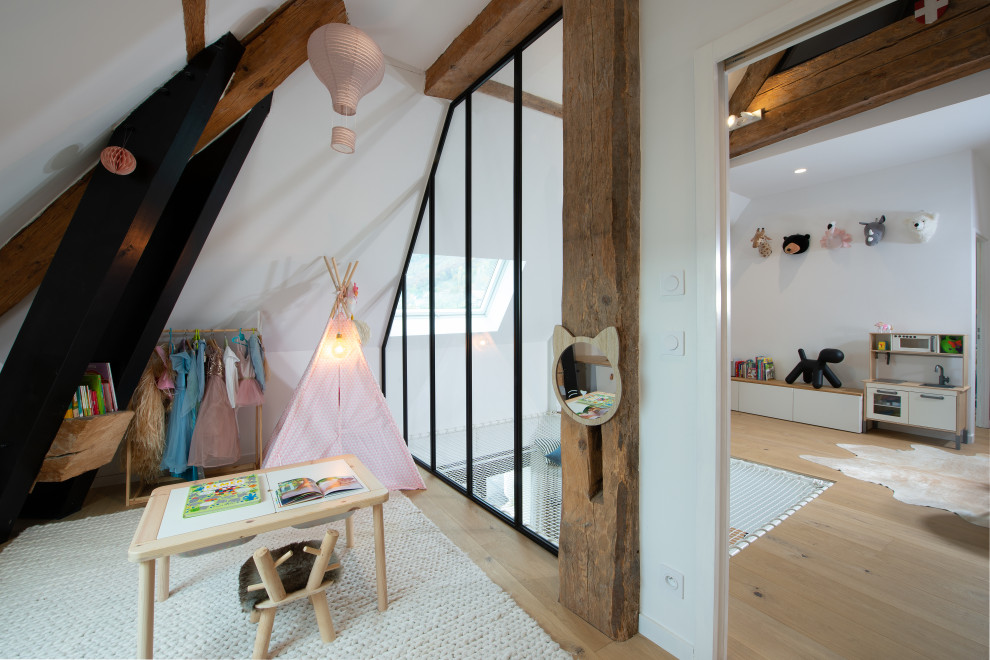 This is an example of a mid-sized modern gender-neutral kids' playroom for kids 4-10 years old in Other with white walls, light hardwood floors and exposed beam.