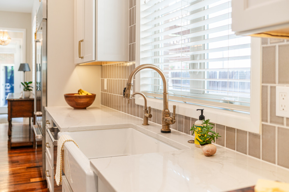 Large transitional l-shaped dark wood floor and brown floor open concept kitchen photo in Denver with a farmhouse sink, shaker cabinets, beige cabinets, quartz countertops, beige backsplash, ceramic backsplash, stainless steel appliances, an island and white countertops