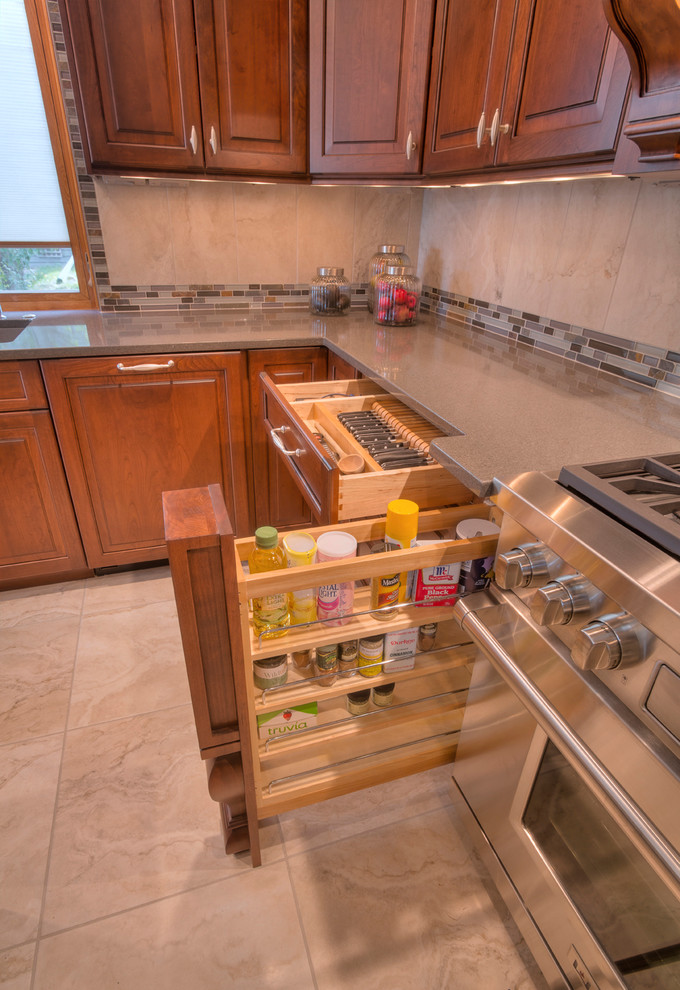 Large transitional l-shaped ceramic tile home design photo with an undermount sink, raised-panel cabinets, medium tone wood cabinets, glass countertops, multicolored backsplash, mosaic tile backsplash, paneled appliances and an island