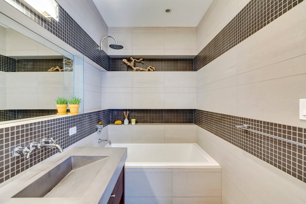 This is an example of a mid-sized contemporary master bathroom in New York with flat-panel cabinets, medium wood cabinets, concrete benchtops, an alcove tub, a two-piece toilet, gray tile, porcelain tile, grey walls and mosaic tile floors.
