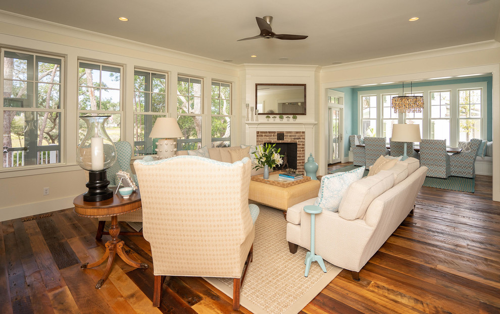 Mid-sized beach style enclosed family room in Atlanta with white walls, medium hardwood floors, a corner fireplace, a brick fireplace surround, no tv and brown floor.