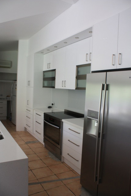Inspiration pour une arrière-cuisine linéaire minimaliste de taille moyenne avec des portes de placard blanches, une crédence grise, un électroménager en acier inoxydable et îlot.