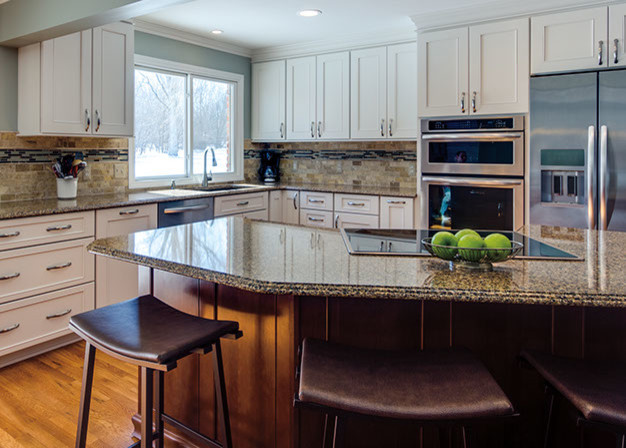 Mid-sized transitional l-shaped eat-in kitchen in Chicago with an undermount sink, beaded inset cabinets, white cabinets, granite benchtops, beige splashback, porcelain splashback, stainless steel appliances, light hardwood floors and with island.