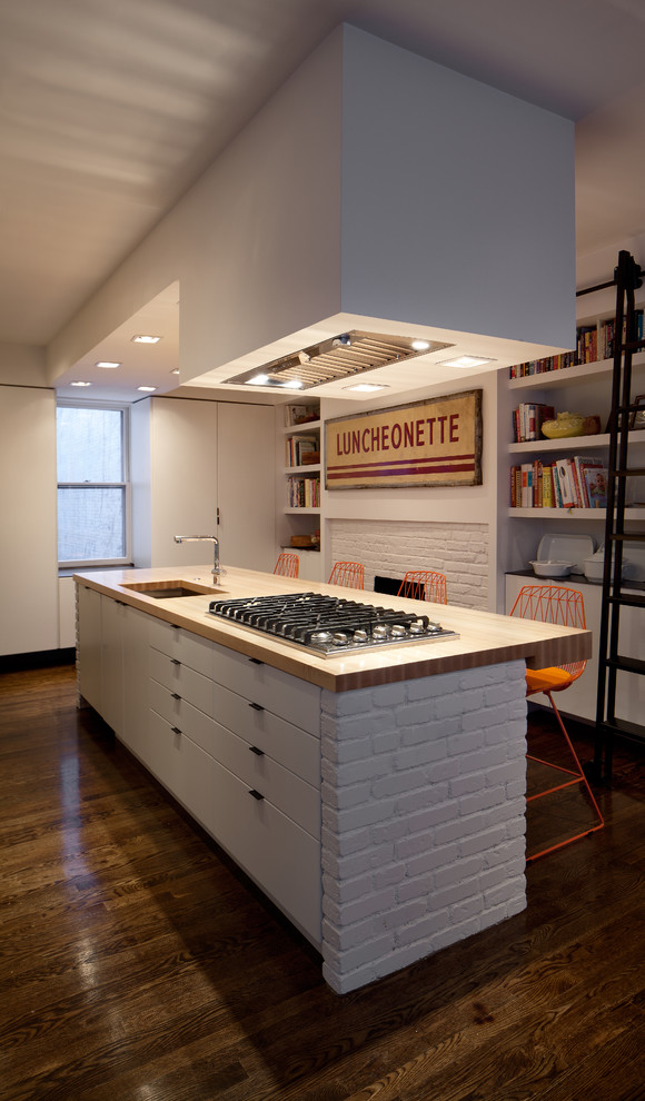 This is an example of a modern eat-in kitchen in Boston with wood benchtops, flat-panel cabinets, white cabinets, an undermount sink and stainless steel appliances.