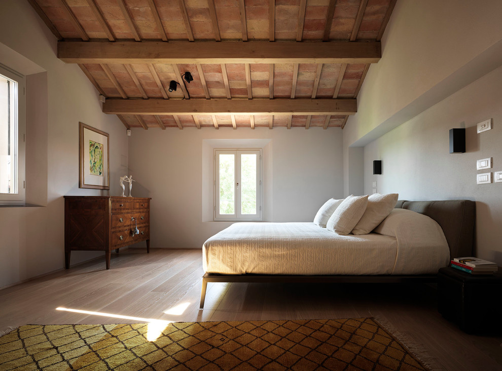 Expansive country guest bedroom in Bologna with light hardwood floors and white walls.