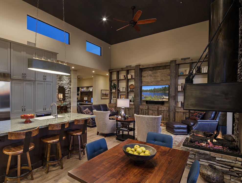 Inspiration for a mid-sized rustic l-shaped light wood floor kitchen remodel in Phoenix with a farmhouse sink, raised-panel cabinets, gray cabinets, granite countertops, beige backsplash, stone tile backsplash, stainless steel appliances and an island