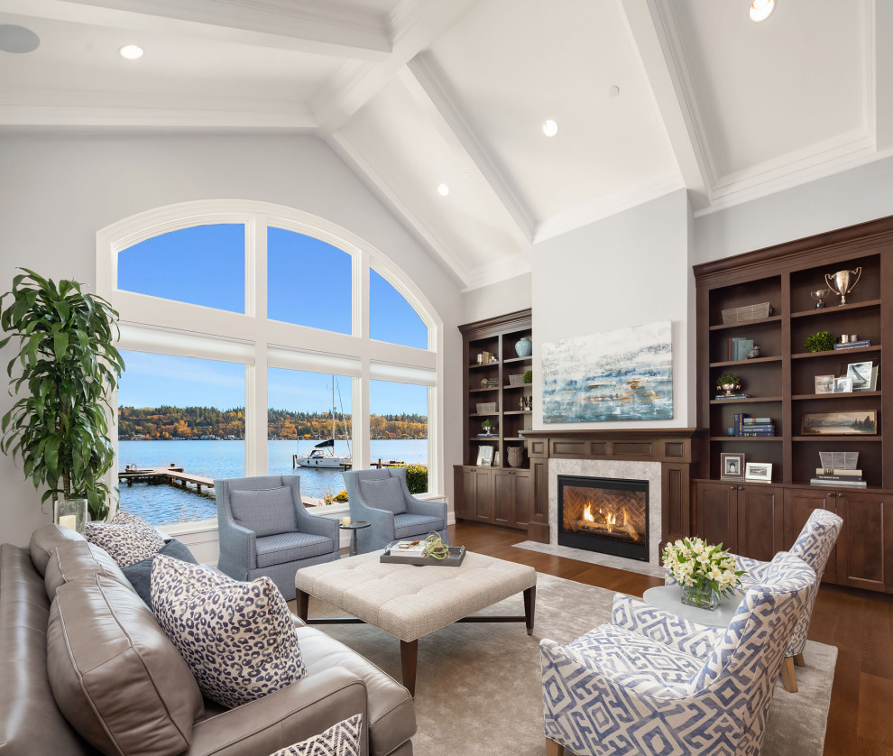 Design ideas for a mid-sized beach style open concept family room in Seattle with grey walls, medium hardwood floors, a standard fireplace, a stone fireplace surround, a concealed tv and brown floor.