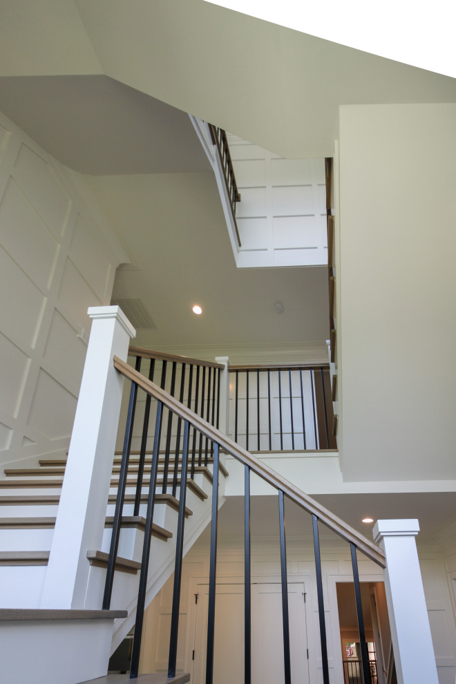 Photo of a large traditional wood u-shaped wood railing staircase in DC Metro with wood risers and wainscoting.