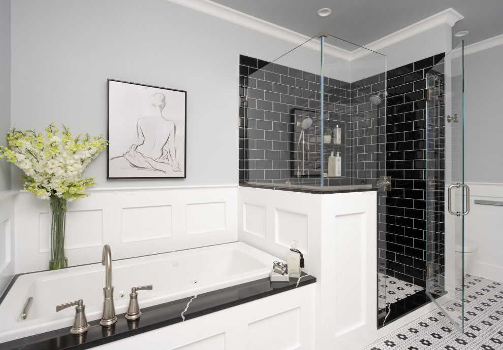This is an example of a large traditional master bathroom in Boston with recessed-panel cabinets, white cabinets, a drop-in tub, an alcove shower, a one-piece toilet, black tile, ceramic tile, grey walls, ceramic floors, an undermount sink, engineered quartz benchtops, multi-coloured floor, a hinged shower door, black benchtops, a niche, a double vanity and a built-in vanity.