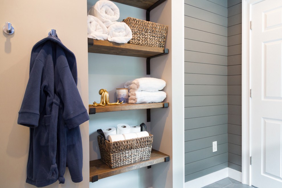 Design ideas for a mid-sized beach style kids bathroom in Boston with shaker cabinets, blue cabinets, an alcove tub, blue tile, an undermount sink, solid surface benchtops, grey floor and white benchtops.