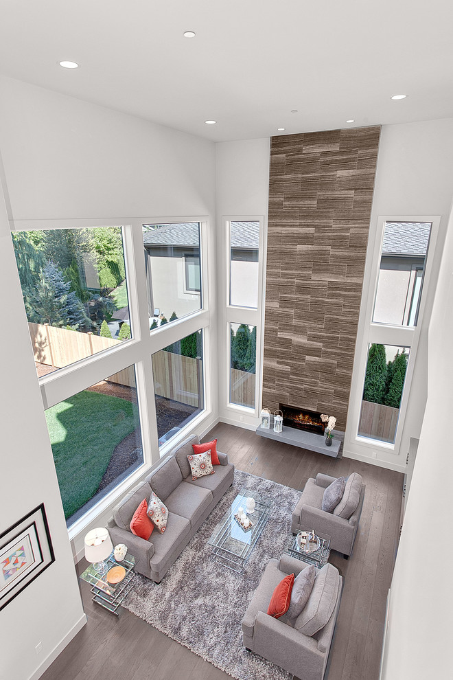 Inspiration for a large contemporary open concept family room in Seattle with white walls, medium hardwood floors, a hanging fireplace, a stone fireplace surround, a wall-mounted tv and grey floor.